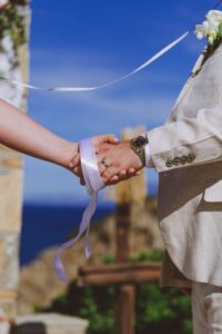A wedding couples hands with a handfasting ribbon used during the exchange of wedding vows.