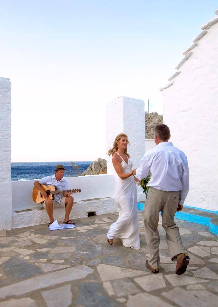 A wedding couple dance as Mark Usher, Musician and wedding DJ in Rhodes, Greece plays for them at their ceremony.