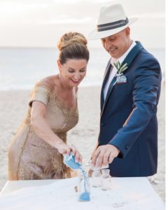 A mature couple complete a sand blending ceremony in a Greek beach wedding ceremony, led by wedding celebrant ECK - a wedding celebrant in Greece