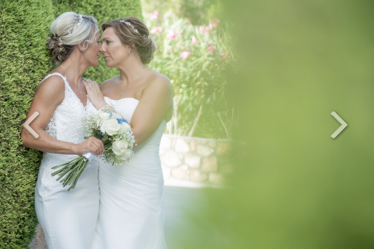 A romantic shot of a lesbian couple on their wedding day amongst some greenery